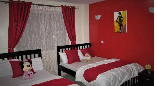 2 camas en un dormitorio con paredes rojas en Rental Furnished Apartment{ Two Bed Room }, en Kisumu