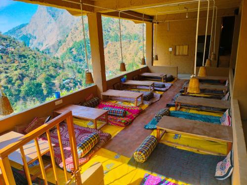 a room with tables and chairs and a mountain view at Pyare Cafe Cottages And Tents in Gushaini