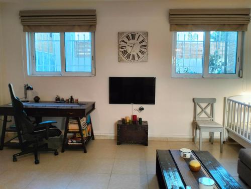 a living room with a desk and a clock on the wall at Studio Melissi Korinthias in Melíssion