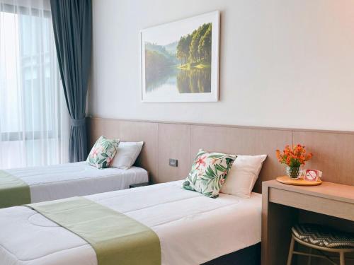 a hotel room with two beds and a table at Sand Dance Hotel in Prachuap Khiri Khan