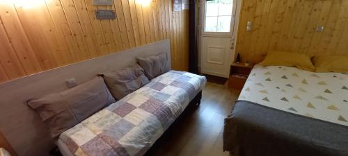 1 dormitorio con 2 camas, ventana y puerta en Chambre d'hôte chez Nathalie & Roland en Massiac
