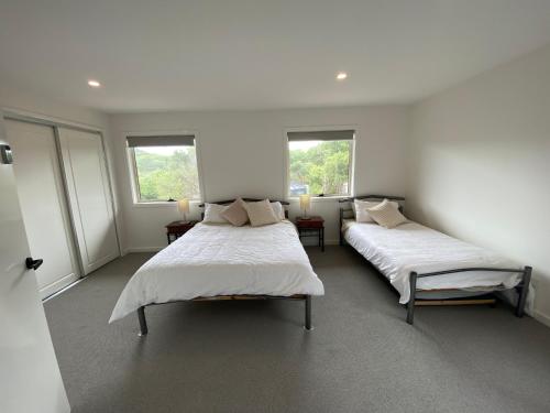 two beds in a room with two windows at Sandy Point Beach Escape 2 Bedroom Apartment in Sandy Point