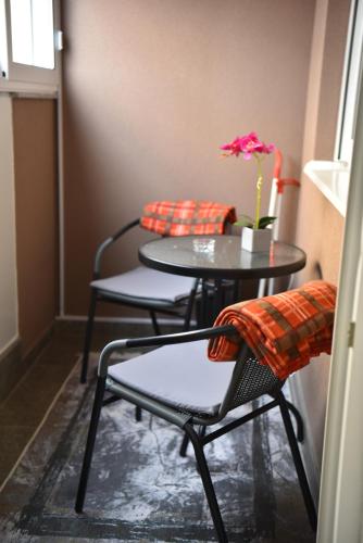 a table and chairs with a vase with a flower at SM apartman in Bijeljina