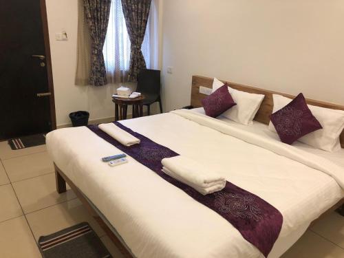 a bedroom with a large bed with white and purple pillows at Hotel Amulya Regency in Bengaluru
