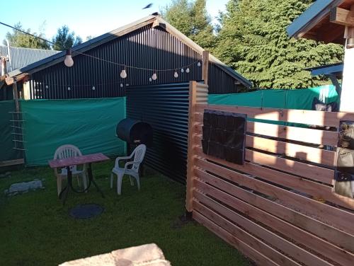 a wooden shed with a table and chairs in a yard at Mini Casa en el Sur in San Martín de los Andes