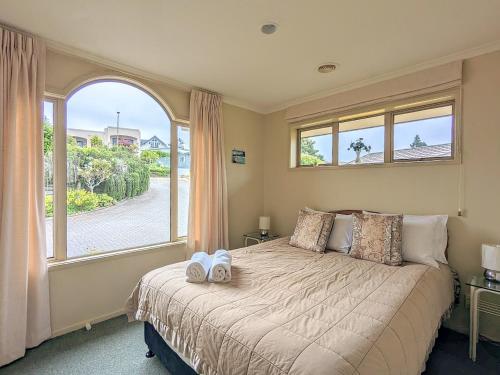 a bedroom with a bed with a large window at Perfect for lake view and city view in Rotorua in Rotorua