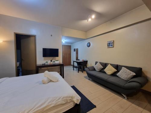 ein Hotelzimmer mit einem Bett und einem Sofa in der Unterkunft Palm Tree Condos near MNL Airport Terminal 3 by ELR in Manila
