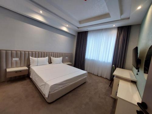 a bedroom with a white bed and a television at EL Faro RESORT AND SPA HOTEL in Nabran
