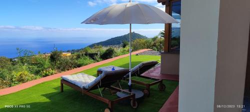 een paar stoelen en een paraplu op een gazon bij La Finca de la bicicleta in Breña Alta