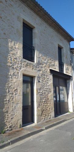 ein Steingebäude mit zwei Türen und zwei Fenstern in der Unterkunft Gîte Terre in Saint-Laurent-de-Médoc