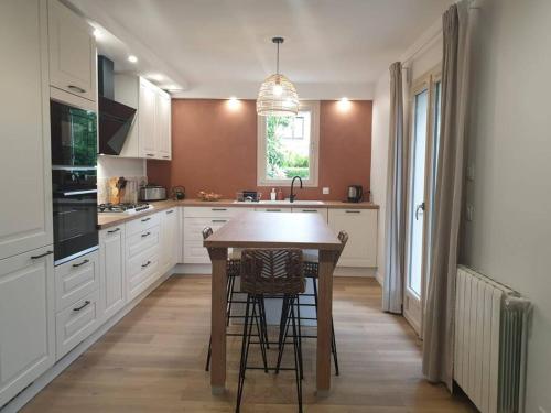 - une cuisine avec une table et quelques tabourets dans l'établissement Maison aux portes de Caen, à Saint-Germain-la-Blanche-Herbe