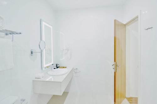 een witte badkamer met een wastafel en een spiegel bij Akomadoo Retreat in Kamadhoo