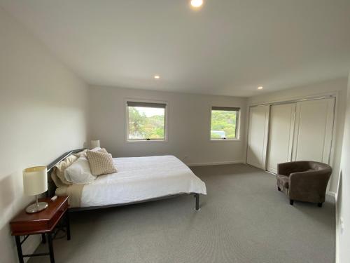 a white bedroom with a bed and a chair at Sandy Point Beach Escape 1 Bedroom Apartment in Sandy Point