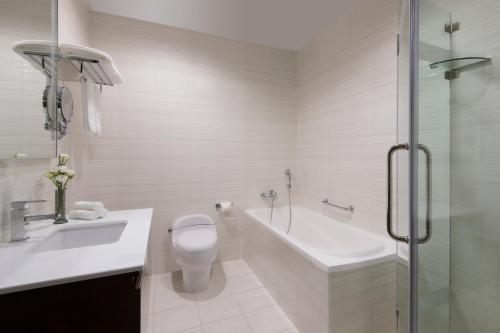 a bathroom with a toilet and a tub and a sink at Marriott Executive Apartments City Center Doha in Doha