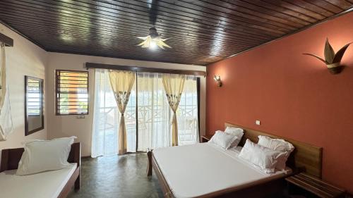 a bedroom with two beds and a large window at VERONIKA Resort Nosy Komba in Nosy Komba