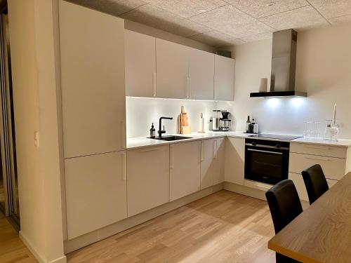 a kitchen with white cabinets and a table with chairs at Luxury New Cozy and Quietly 95m2 in Tórshavn