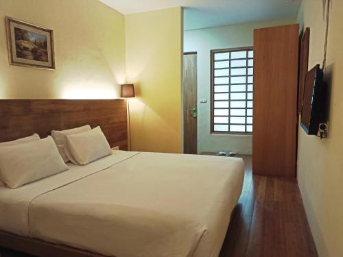 een slaapkamer met een bed, een televisie en een raam bij Malino Highlands in Malino