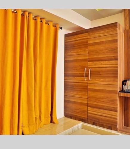 een kamer met gele gordijnen en een houten deur bij Tak International Hotel in Udaipur
