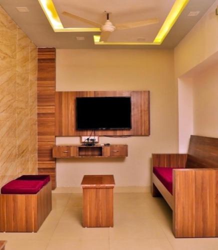 een woonkamer met een flatscreen-tv aan de muur bij Tak International Hotel in Udaipur