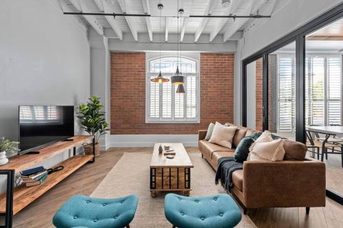 a living room with a couch and a tv at Luxurious Woolstore Living! ~Teneriffe in Brisbane