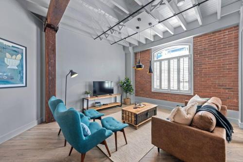 a living room with a couch and chairs and a brick wall at Luxurious Woolstore Living! ~Teneriffe in Brisbane