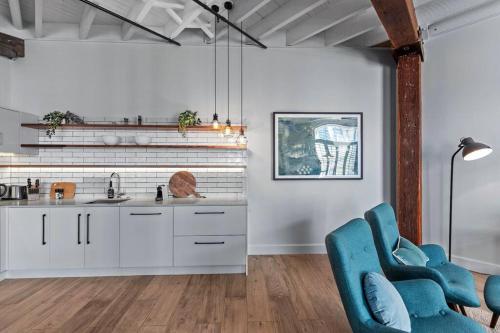 a kitchen with white cabinets and blue chairs at Luxurious Woolstore Living! ~Teneriffe in Brisbane
