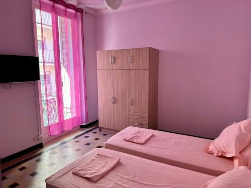 - une chambre avec 2 lits, une armoire et des murs roses dans l'établissement APPARTEMENT N°1 LES CLEMATITES, à Menton