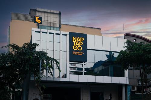 un bâtiment avec un grand panneau sur son côté dans l'établissement NapTapGo - Japanese Premium POD Hotel - Walk to Noida Electronic City Metro! Wifi, Lounge, à Noida