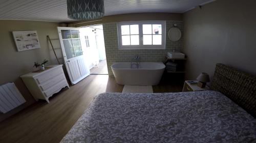 une chambre avec un lit, une baignoire et un lavabo dans l'établissement La cousinade No, à Noirmoutier-en-l'lle