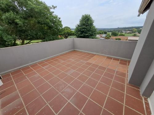 a balcony with a tile floor and a fence at Woodhills Guest house in Piet Retief