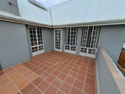 an empty patio of a house with a tile floor at Woodhills Guest house in Piet Retief