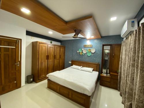 a bedroom with a bed and wooden furniture and a ceiling at AL-MANAL 203 Luxury Suite Rooms 3BHK in Bhatkal