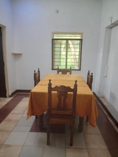 un comedor con una mesa amarilla y una ventana en Aurodham, en Auroville