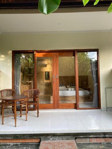a patio with a table and chairs and glass doors at Nataliya Homestay in Ubud
