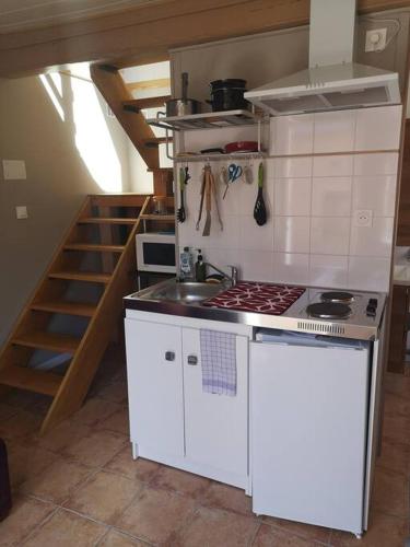 a kitchen with a stove and a sink and a staircase at La coco's house in Planchez
