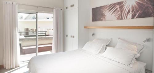 um quarto branco com uma cama grande e uma janela em Spacieux appt 2ch 50m de la plage em Cap Malheureux