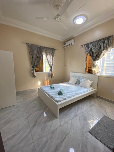 1 dormitorio con 1 cama en una habitación con ventanas en KMR Apartment - Kumba en Serekunda