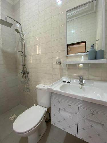 La salle de bains blanche est pourvue de toilettes et d'un lavabo. dans l'établissement KMR Apartment - Kumba, à Serekunda