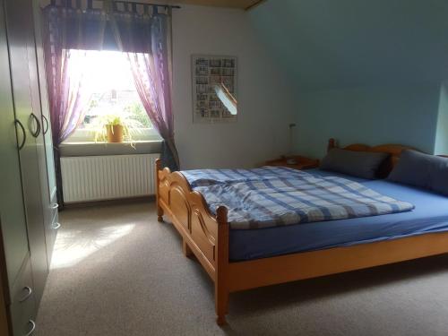 um quarto com uma cama com um edredão azul e uma janela em Fewo Am Heidestrandbad em Hemmoor