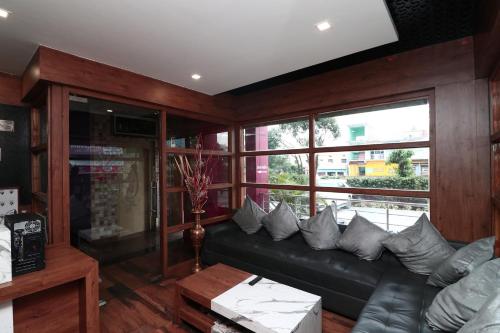 sala de estar con sofá de cuero negro con almohadas en Collection O Jatin hotel, en Haldwāni
