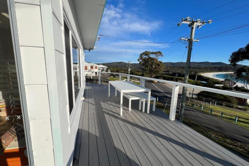 a balcony with a white bench on a house at PIPI SHACK - iconic waterfront shack Binalong Bay in Binalong Bay