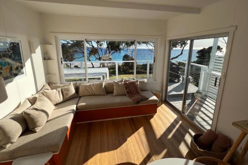 a living room with a couch and a view of the ocean at PIPI SHACK - iconic waterfront shack Binalong Bay in Binalong Bay