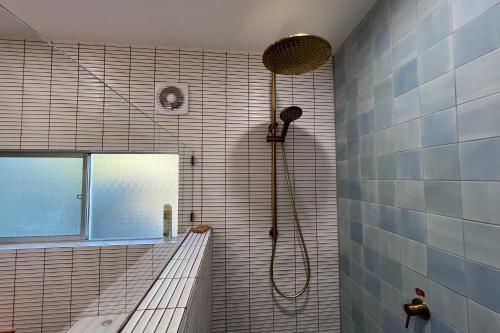 a bathroom with a shower with a shower head at PIPI SHACK - iconic waterfront shack Binalong Bay in Binalong Bay