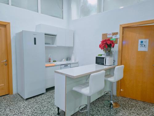 eine weiße Küche mit einer Theke und einem Kühlschrank in der Unterkunft CAPSULE INN VALENCIA Hostel in Valencia