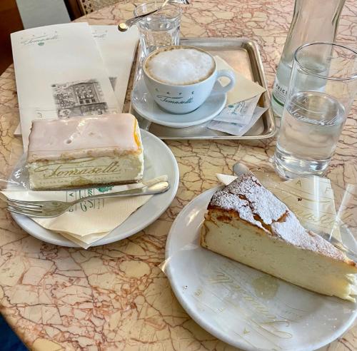 een tafel met twee plakjes cake en een kop koffie bij River Lilly Apartment in Obertraun