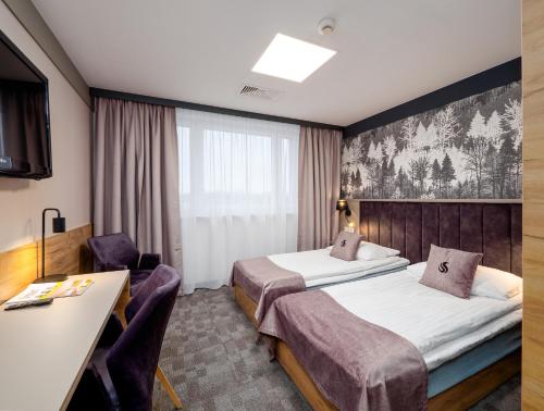 una camera d'albergo con 2 letti e una scrivania di Hotel Scout a Częstochowa