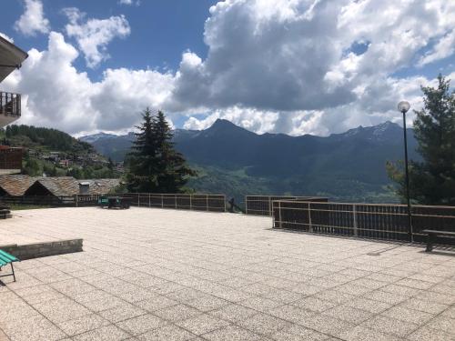 una panchina su un patio con montagne sullo sfondo di Monolocale Torgnon “ Plein Soleil” a Torgnon