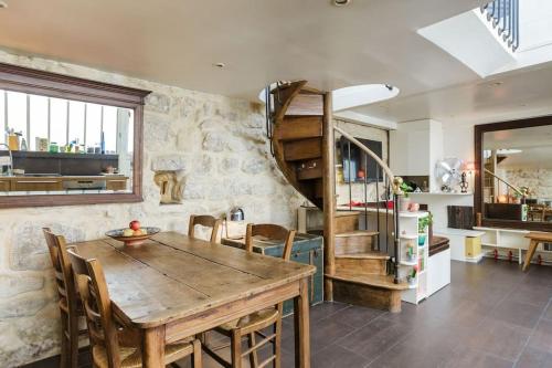 une salle à manger avec une table en bois et un escalier en colimaçon dans l'établissement Peace and greenery, heart of Paris, à Paris