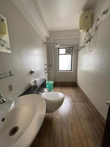 a bathroom with a white sink and a toilet at Hotel Sundaram Palace in Siliguri