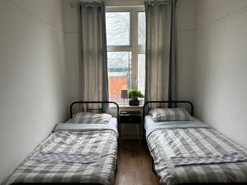 dwa łóżka w pokoju z oknem w obiekcie barnet 2 w mieście Barnet